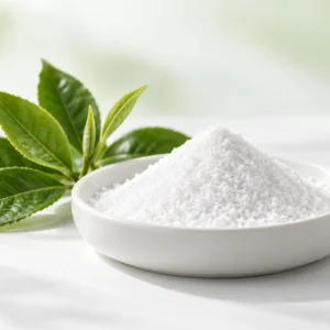 White L-Theanine powder in a ceramic dish beside green tea leaves