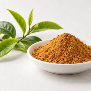 Golden-yellow to reddish-brown Theaflavin powder in a white dish beside green tea leaves